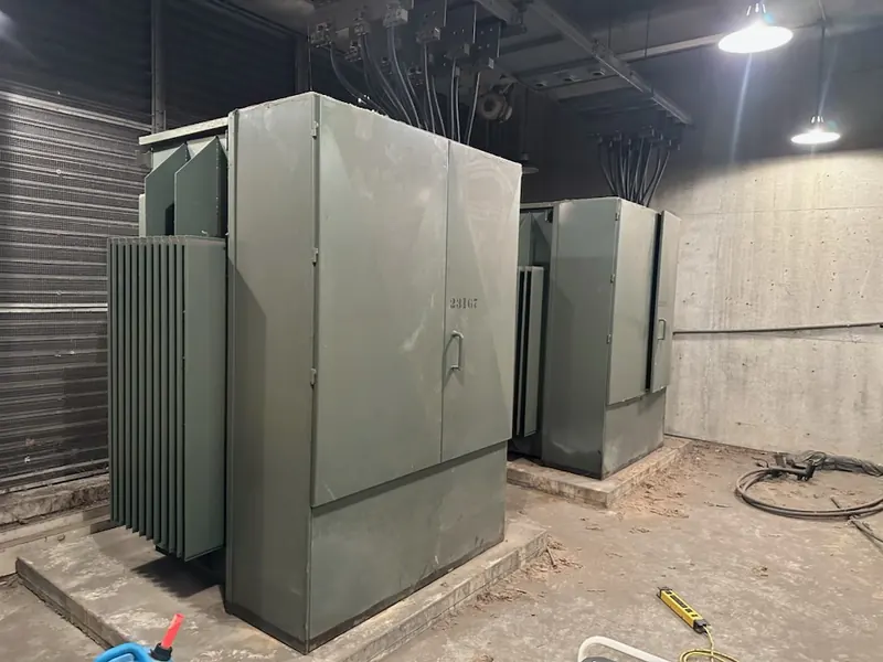 Two large electrical transformer units installed inside an industrial electrical room